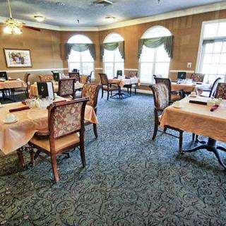 An elegant dining area with neatly arranged tables and chairs, featuring large windows and classic decor.