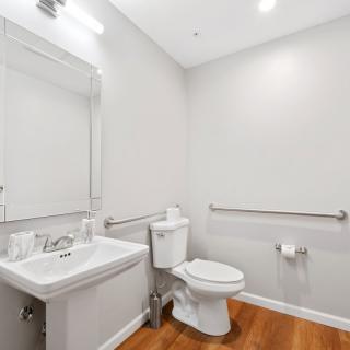 A modern minimalist bathroom with a sink, toilet, and large mirror.