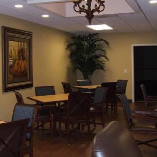 A cozy dining area with tables, chairs, a decorative plant, and artwork on the wall.
