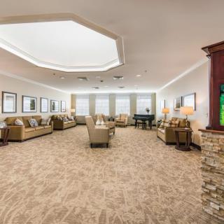 A spacious and elegantly decorated living room with multiple seating areas, featuring sofas, chairs, and a grand piano.
