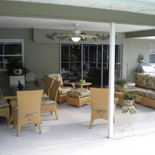 A cozy patio with wicker furniture and a ceiling fan, perfect for outdoor relaxation.