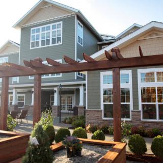 A modern residential building with a landscaped garden and wooden pergola.