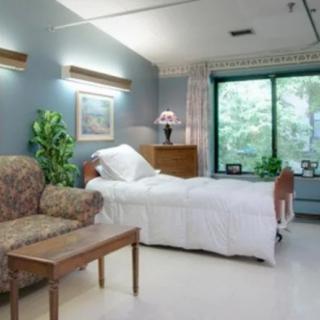 A well-lit hospital room with a patient bed, chair, and window view.