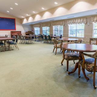 A spacious community center meeting room with tables and chairs arranged on a carpeted floor.
