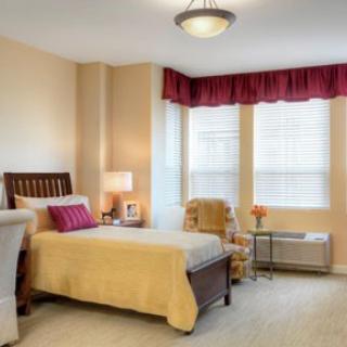 A cozy bedroom with elegant furnishings, featuring a single bed, a comfortable chair, and soft lighting.