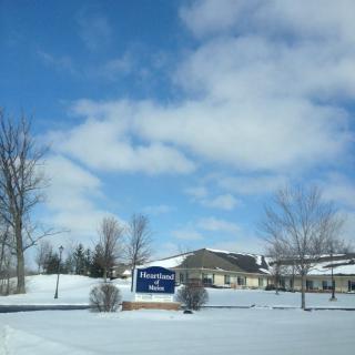 A hotel surrounded by a snowy landscape under a partly cloudy blue sky.