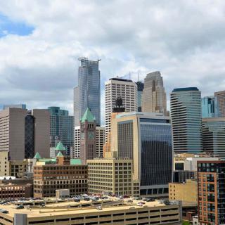 A vibrant city skyline with a mix of modern skyscrapers and historic architecture under a partly cloudy sky.