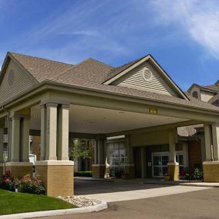 An exterior view of a building entrance with an awning supported by pillars.
