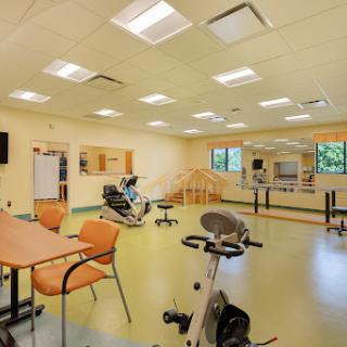 A spacious rehabilitation exercise room equipped with various gym apparatus for physical therapy.