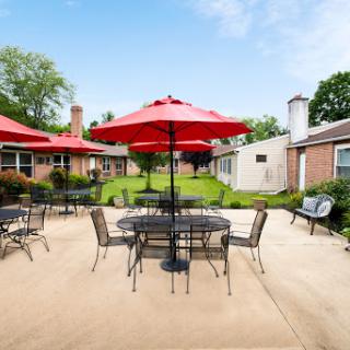 A beautifully arranged outdoor patio featuring red umbrellas and tables, perfect for gatherings.