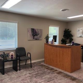 A modern reception area featuring a wooden front desk, comfortable seating, and decorative plants.
