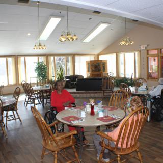 A cozy dining area with seniors seated at wooden tables, featuring a warm and inviting atmosphere.