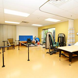 A spacious rehabilitation room filled with various exercise equipment designed for physical therapy.
