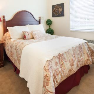 A cozy bedroom with a neatly made bed, featuring patterned bedding and decorative pillows.