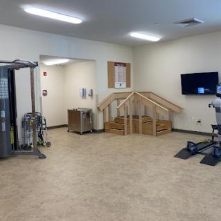 A spacious rehabilitation gym featuring various exercise equipment and a stair training area.
