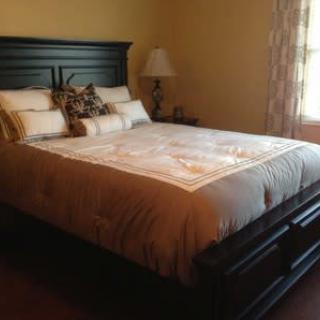 A cozy bedroom featuring a neatly made bed with decorative pillows and a bedside lamp.