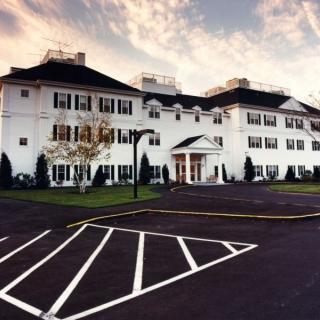 A grand white hotel with a spacious parking area in the foreground.