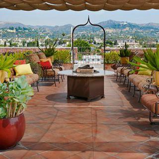 A stylish rooftop patio with comfortable seating, lush plants, and a scenic view of the surrounding hills.