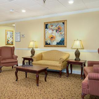 A cozy living room featuring a sofa, chairs, and a coffee table with decorative lamps and artwork on the wall.