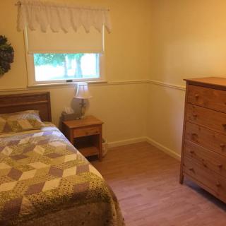 A cozy bedroom with a single bed, dresser, and nightstand.