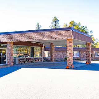 A modern commercial building with a brick facade, featuring large windows and a spacious parking area.