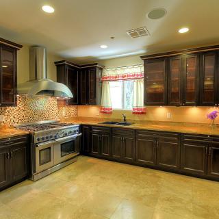 A modern kitchen with dark wood cabinets, stainless steel appliances, and a tile backsplash.