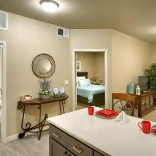 A modern interior featuring a kitchen with a dining area and a view into the bedroom, showcasing tasteful home decor.