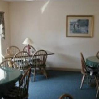 A cozy dining room with multiple tables and chairs, featuring a lamp and wall art.