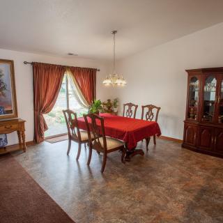 A traditional dining room with a red tablecloth on the table, surrounded by chairs, and a chandelier overhead.