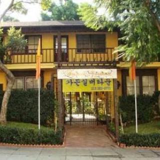 A yellow two-story house with a banner across the entrance, surrounded by trees.