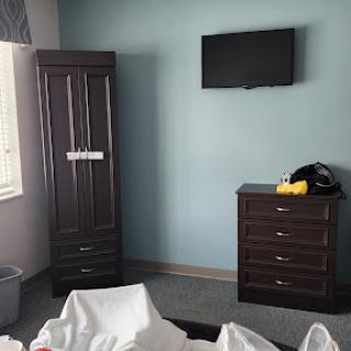 A view of a simple bedroom featuring a wardrobe, dresser, and wall-mounted television.