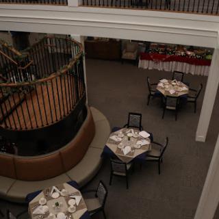 An elegant restaurant interior featuring well-set dining tables and a decorative staircase.