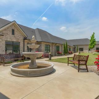 A peaceful courtyard with a central fountain, surrounded by benches and landscaped gardens in a residential setting.