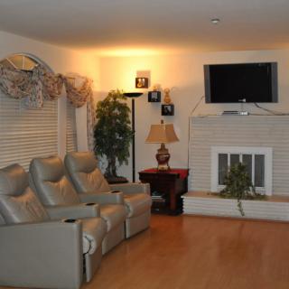 A cozy living room featuring recliner seating, a television mounted above the fireplace, and tasteful decor.