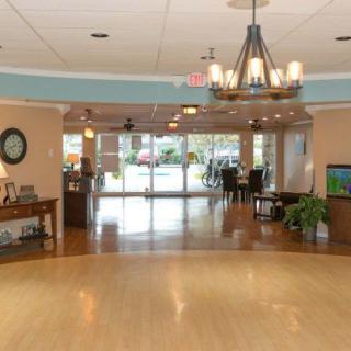 Spacious lobby with a chandelier and hardwood floors leading to an entrance.