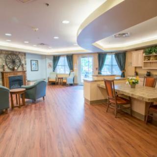 A spacious and well-lit living room featuring a fireplace, seating area, and dining table with wooden flooring.