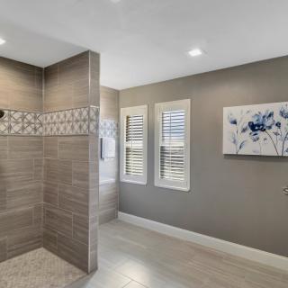 A modern bathroom featuring a tiled shower and framed artwork on the wall.