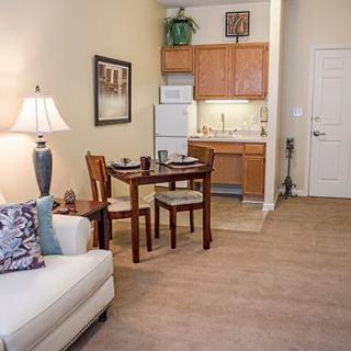 A cozy apartment with an open-concept living and dining area, featuring a sofa, a small dining table with chairs, and a compact kitchen.