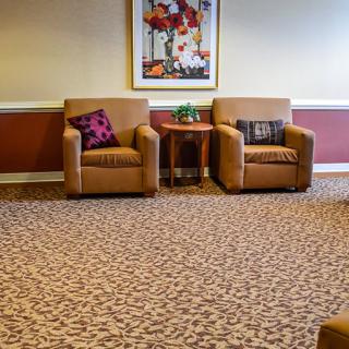 A cozy lounge area with two armchairs and a small table set against a decorative wall.