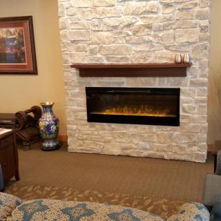 A cozy living room with a modern electric fireplace set in a stone wall.