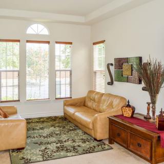 A cozy living room with leather sofas, a patterned rug, and large windows letting in natural light.