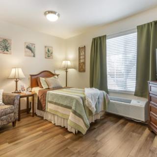 A cozy bedroom with a single bed, wooden floor, and elegant decor.