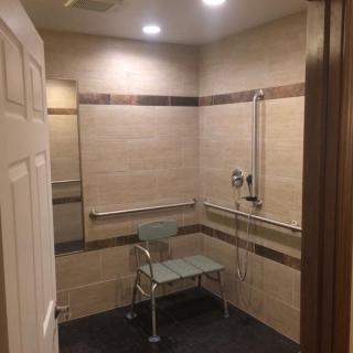 An accessible bathroom with a shower seat and grab bars.