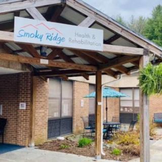 The entrance of Smoky Ridge Health & Rehabilitation Center, featuring outdoor seating and a welcoming sign.