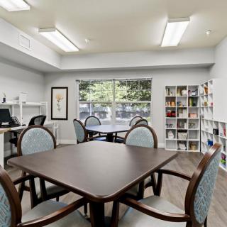 A cozy library reading room with tables, chairs, and bookshelves.