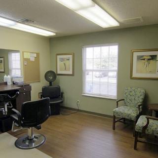 A cozy barber shop interior featuring chairs, a mirror, and artwork on the walls.