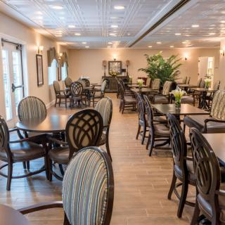 Elegant dining area with arranged tables and chairs, featuring warm lighting and greenery.
