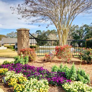 A beautifully landscaped garden with vibrant flowers and a decorative fence under a clear blue sky.