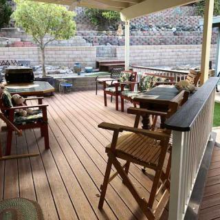 A cozy outdoor patio with wooden decking, featuring various seating arrangements and greenery.
