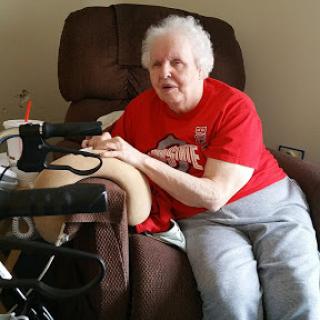 An elderly woman relaxing in a chair, engaged in a healthcare activity.